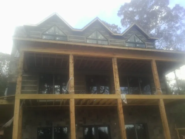 Dormers and porch framing on a large log home under construction — Roof Coating work by our crew in Rantoul