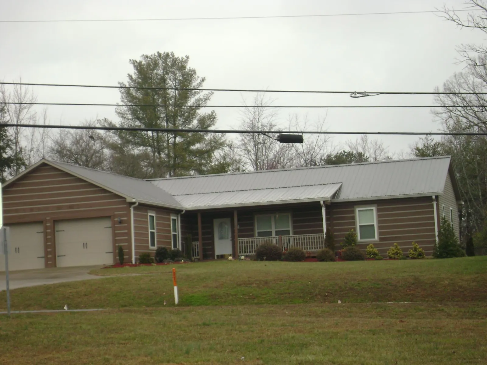 Gray metal roof on a log sided ranch home with a front porch in Rantoul