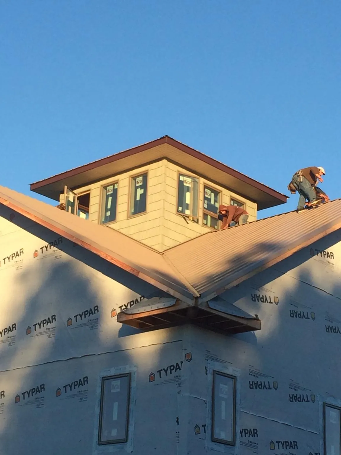 Roofers working around a rooftop cupola on a new metal roof at sunset — Roof Waterproofing in Rantoul by Roofing Brothers